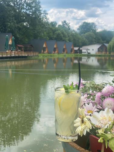 a drink sitting on a table next to a body of water at Pastravaria Zavoi in Valea Danului
