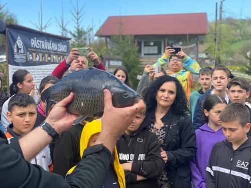 a crowd of people holding a fish in their hands at Pastravaria Zavoi in Valea Danului