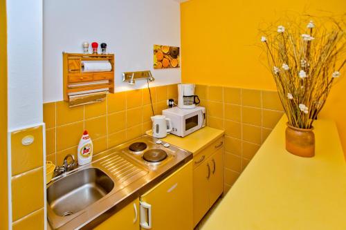 a yellow kitchen with a sink and a microwave at Villa Softic in Hvar