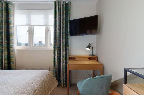 a bedroom with a desk and a bed and a television at The Oxford Lodge - Ensuite Rooms in Oxford