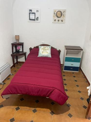 a large red bed in a room with a floor at Alojamiento Orellana in Orellana la Vieja