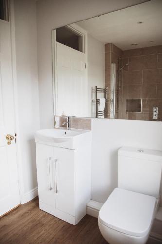 a white bathroom with a toilet and a sink at Glebe House in Barford Saint Martin