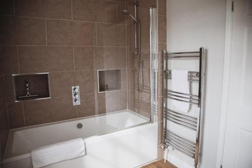 Barford Saint Martin的住宿－Glebe House，浴室配有浴缸、淋浴和毛巾。