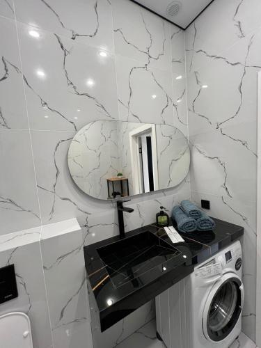 a bathroom with a washing machine and a mirror at Дизайнерская квартира ЖК Шанырак 33 in Pavlodar