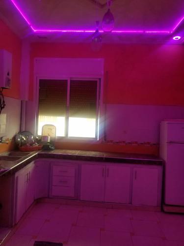 een keuken met paarse verlichting op de muren bij تجزئة البلغيتي أزرو in Azrou