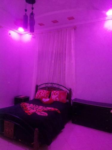 een paarse kamer met een bed met roze verlichting bij تجزئة البلغيتي أزرو in Azrou