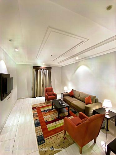 a living room with a couch and chairs and a tv at بيوتات المروة للشقق المخدومة biutat almarwa in Jeddah