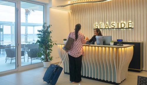 a woman standing at a cash register in an office at Seaside Hotel in Capo dʼOrlando
