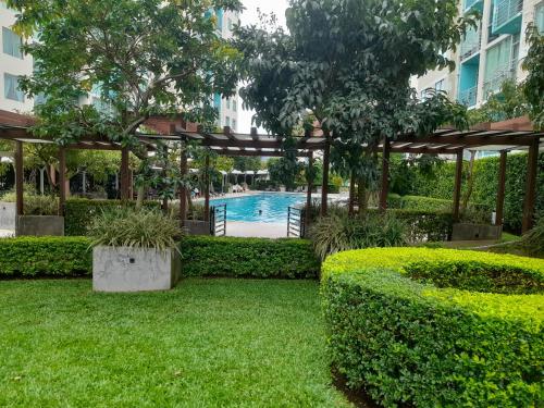 a garden with a swimming pool and a pergola at Lujoso condominio con lavadora y secadora, S. José in San José