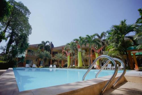 a swimming pool with palm trees and a building at Coconut Beach Resort, Koh Chang in Ko Chang