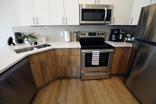 a kitchen with stainless steel appliances and wooden cabinets at Downtown 3 Queen Beds, AC, Double Garage, Disney in Edmonton