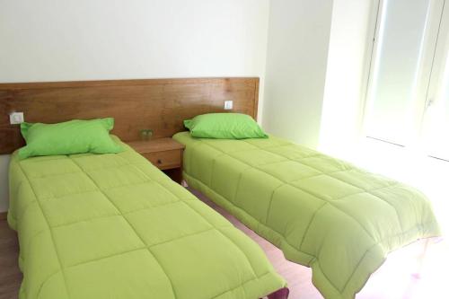 two beds in a room with green sheets at 7 bedrooms house with private pool enclosed garden and wifi at Corte de Pao E Agua in Corte de Pão e Água