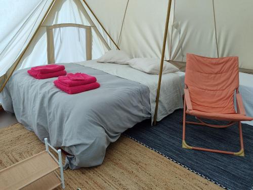 a bed and a chair in a tent at LES JARDINS CELESTES in Saint-Genest-de-Bauzon