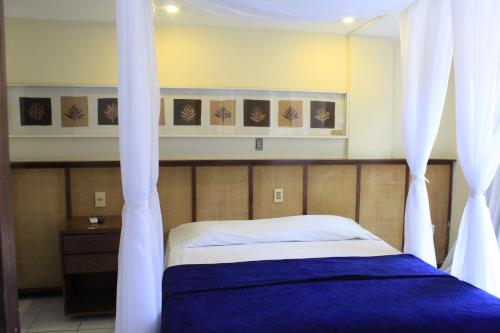 a bed with white curtains in a bedroom at Sunbrazil Hotel - Antigo Hotel Terra Brasilis in Natal