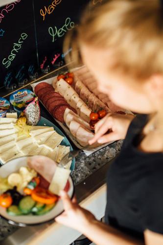 a woman standing in front of a buffet of food at Beach Motel St. Peter-Ording in Sankt Peter-Ording