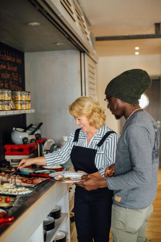 a man and a woman standing at a counter in a kitchen at Beach Motel St. Peter-Ording in Sankt Peter-Ording