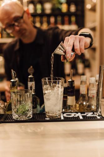 a man is pouring a drink into a glass at Beach Motel St. Peter-Ording in Sankt Peter-Ording