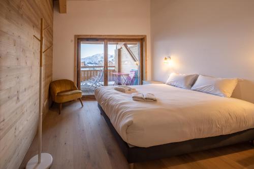une chambre avec un grand lit et un balcon dans l'établissement Alpe d'Huez Houses - Chez Ernest - Gentianes - Magnifique 1 chambre cabine, à L'Alpe-d'Huez