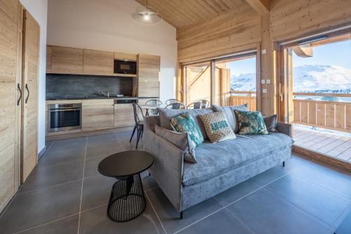 un salon avec un canapé et une table dans l'établissement Alpe d'Huez Houses - Chez Ernest - Gentianes - Magnifique 1 chambre cabine, à L'Alpe-d'Huez