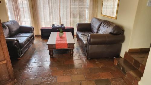 a living room with two leather chairs and a coffee table at SABLE INN B&B in Modimolle