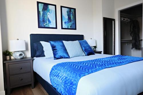 a bedroom with a blue and white bed and two pictures at Downtown 3 Queen Beds, AC, Double Garage, Disney in Edmonton