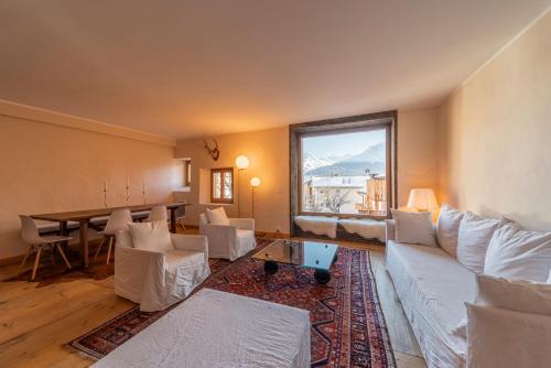 een woonkamer met witte meubels en een groot raam bij Alte Scheune - Samedan in Samedan