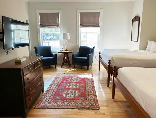 a bedroom with two beds and two chairs and a television at The Shire Woodstock in Woodstock