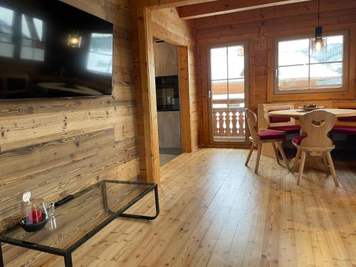 ein Wohnzimmer mit einem großen TV und einem Tisch in der Unterkunft Chalet Kleinbergsonne in Filzmoos