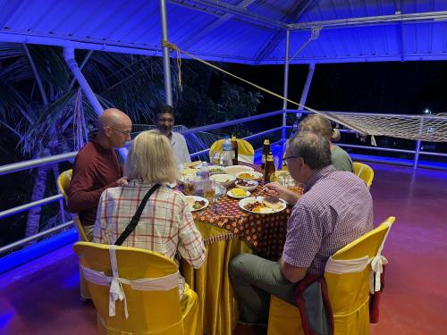 a group of people sitting around a table eating food at Marari Beach Villas in Mararikulam