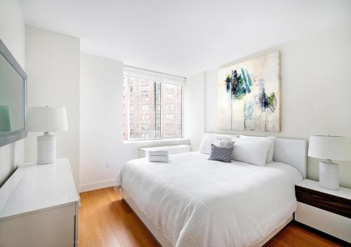 a white bedroom with a bed and a tv at Stunning 2 BED 2 BA At UES in New York