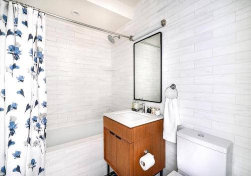 Stunning 2 BED 2 BA At UES في نيويورك: حمام مع حوض ومرآة ومرحاض