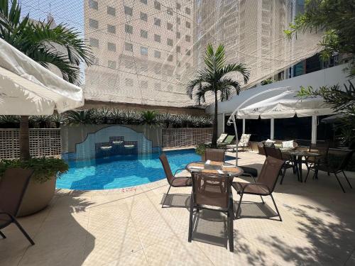 a patio with tables and chairs and a swimming pool at Flat Funchal JK Vila Olímpia Limpeza Diária in Sao Paulo
