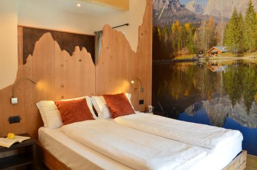 a bedroom with a large bed with a painting on the wall at Aria Alpina Guest House Affittacamere in Predazzo