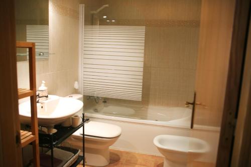 een badkamer met een wastafel, een toilet en een bad bij Apartamento Gis con chimenea in Ribes de Freser