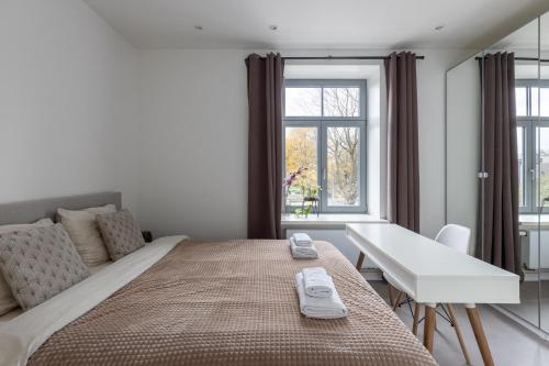 a bedroom with a bed and a desk and a window at Ķīpsala apartments with free parking in Riga