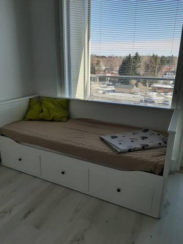 a bed in a room with a large window at Kompakti studio in Tampere