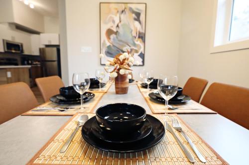 a dining room table with black plates and wine glasses at Downtown 3 Queen Beds,Double Garage,Disney+ in Edmonton