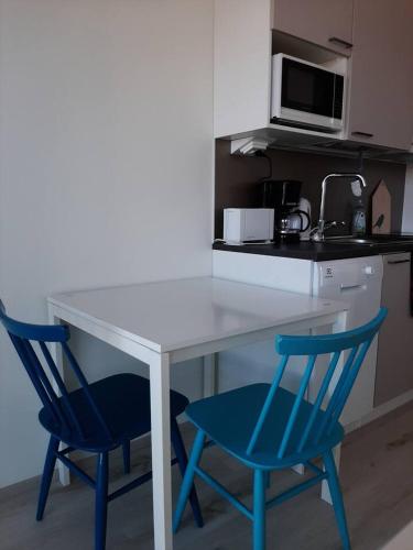 a white table with two blue chairs in a kitchen at Kompakti studio in Tampere