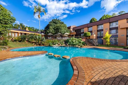 a swimming pool in front of a building at African Sky Hotels - Pine Lake Inn in White River