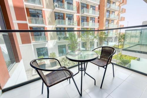 einen Balkon mit einem Glastisch und 2 Stühlen in der Unterkunft One Bed Apartment in Dubai - Dubai South - Damac Celestia in Dubai