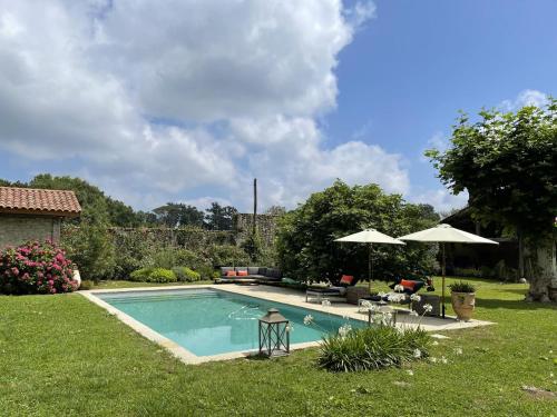 - une piscine dans une cour avec des parasols dans l'établissement Les ecuries du chateau, à Biaudos