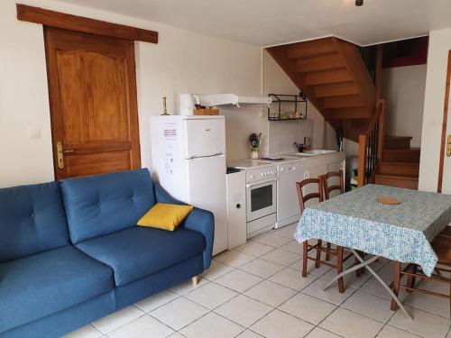 a living room with a blue couch and a kitchen at Logement 'la Hulotte'-10 min d'Auxerre-2h de Paris 