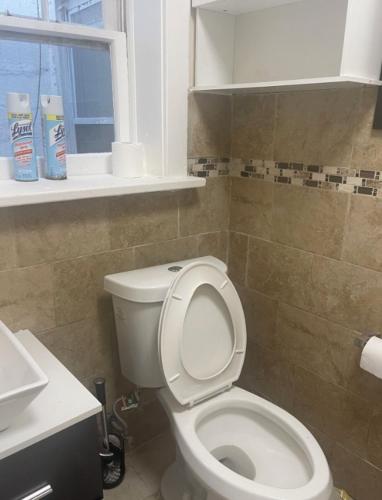 a bathroom with a toilet and a sink and a window at Trendy 2BR apartment in NYC! in New York