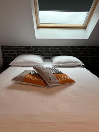 a bed with two pillows on it with a window at La maison du bonheur avec clim reversible in Larçay