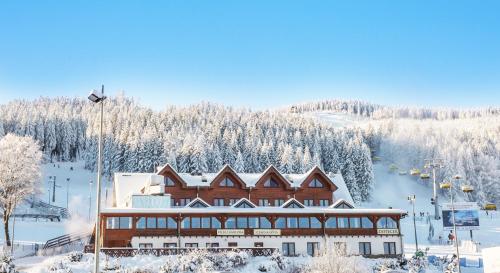 budynek na stoku narciarskim z pokrytymi śniegiem drzewami w obiekcie Karczma Czarna Góra - Czarna Góra Resort w Stroniu Śląskim