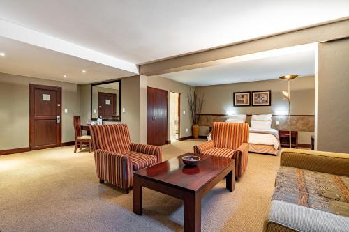 a hotel room with a bed and chairs and a table at African Sky Hotels - Pine Lake Inn in White River