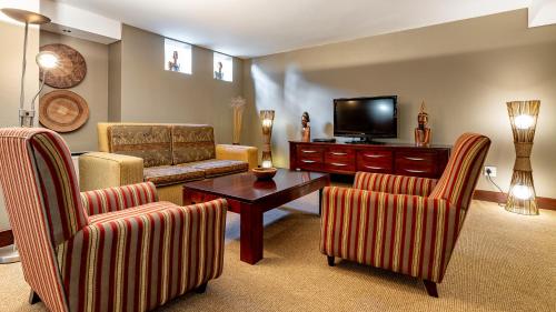 a living room with two chairs and a television at African Sky Hotels - Pine Lake Inn in White River