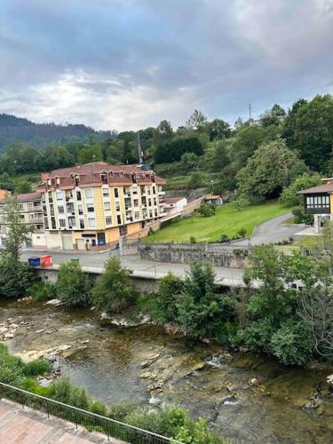 a building next to a river next to a building at Apartamento con vistas a la montaña in Infiesto
