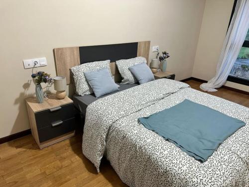 a bedroom with a large bed with blue pillows at Apartamento con vistas a la montaña in Infiesto