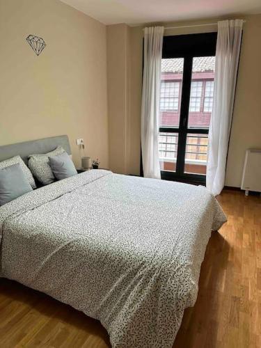 a bedroom with a bed and a large window at Apartamento con vistas a la montaña in Infiesto